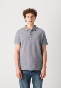 Polo gris con cuello en contraste azul marino y detalles en verde. Tiene tres botones y un pequeño logo en el pecho. Tejido suave y texturizado.