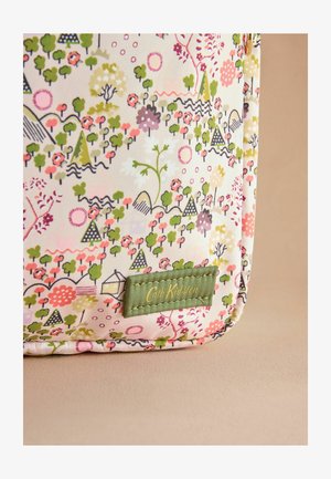 Tkanina za torbo s cvetličnim vzorcem v odtenkih roza, zelene in smetane, z vidno zeleno oznako, na kateri piše "Cath Kidston" v zlati barvi.