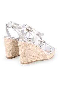 Sandalias de cuña de imitación de piel plateada con tacones de yute trenzados, que presentan tiras entrecruzadas y una textura mate suave.