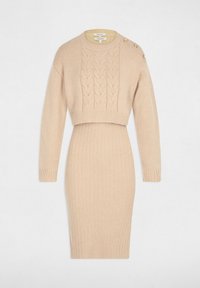 Abito a maglia beige con una texture a coste. Presenta un top corto a trecce e maniche lunghe. Accentuato con bottoni sulla spalla.