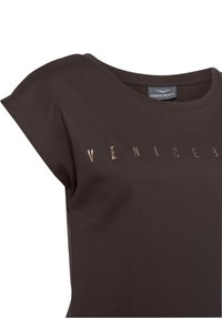 Brown cotton T-shirt with short, rolled sleeves. Features embossed "VENICE BEACH" letters in a metallic finish across the chest.