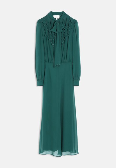 Robe longue vert sarcelle à manches longues, devant froncé et nœud noué au col, suspendue sur un fond blanc.