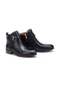 Bottes noires en cuir jusqu'à la cheville avec un embout arrondi, fermeture éclair sur le côté et une sangle décorative avec une boucle dorée. Talon plat, texture lisse.