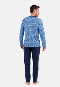 Blaues Langarm-Pyjama-Oberteil mit einem Blättermuster, kombiniert mit navyfarbenen Hosen. Weicher Stoff, lässige Passform und runder Ausschnitt.