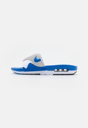 Sandale slide Nike bleu et blanc avec une bride grise ornée du logo Nike bleu et un coussin d'air visible dans la semelle.