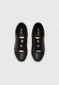 Black leather sneakers with gold accents, featuring a smooth texture, lace-up design, and logo detailing on the tongue and laces.