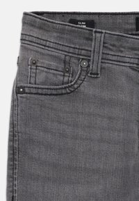 Gray slim-fit jeans with a smooth texture, five pockets, subtle stitching, and black hardware accents on the waist and pockets.