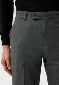 Grijze op maat gemaakte broek, vervaardigd uit een gladde stof met een subtiele textuur, met een vlakke voorkant, riemlussen en een scherpe plooi langs het been.