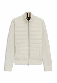 Helle Creme Bomberjacke mit gestepptem oberen Teil und weichen Ärmeln. Ausgestattet mit einem Frontreißverschluss, Seitentaschen sowie gerippten Bündchen und Kragen.
