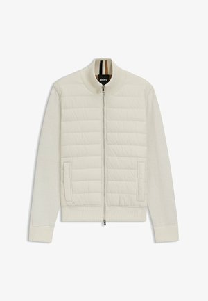 Light cream bomber jacket with quilted upper panel and soft sleeves. Features a front zipper, side pockets, and ribbed cuffs and collar.