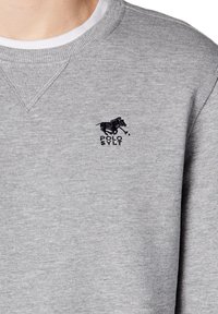 Szary sweatshirt z teksturowanej bawełny. Posiada okrągły dekolt, żeberkowane akcenty oraz haftowane czarne logo konia i napis "POLO SYLT."
