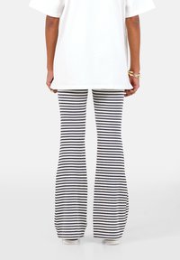 Witte oversized t-shirt gecombineerd met gestreepte flared broek in marineblauw en wit, met een geribbelde textuur en een wijd-pijp ontwerp.