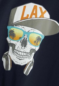 Grafiškai atspausdinta marškinėliai su kaukole, dėvinčia pilką kepuraitę su šriftu "LAX", mėlynomis akinių nuo saulės ir juodais ausiniais ant tamsiai mėlynos fono.