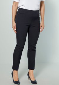 Svarta, stretchiga byxor som dras på med en slät yta, slim fit, längd till anklarna och med resårmidja, kombinerat med mörka högklackade skor.