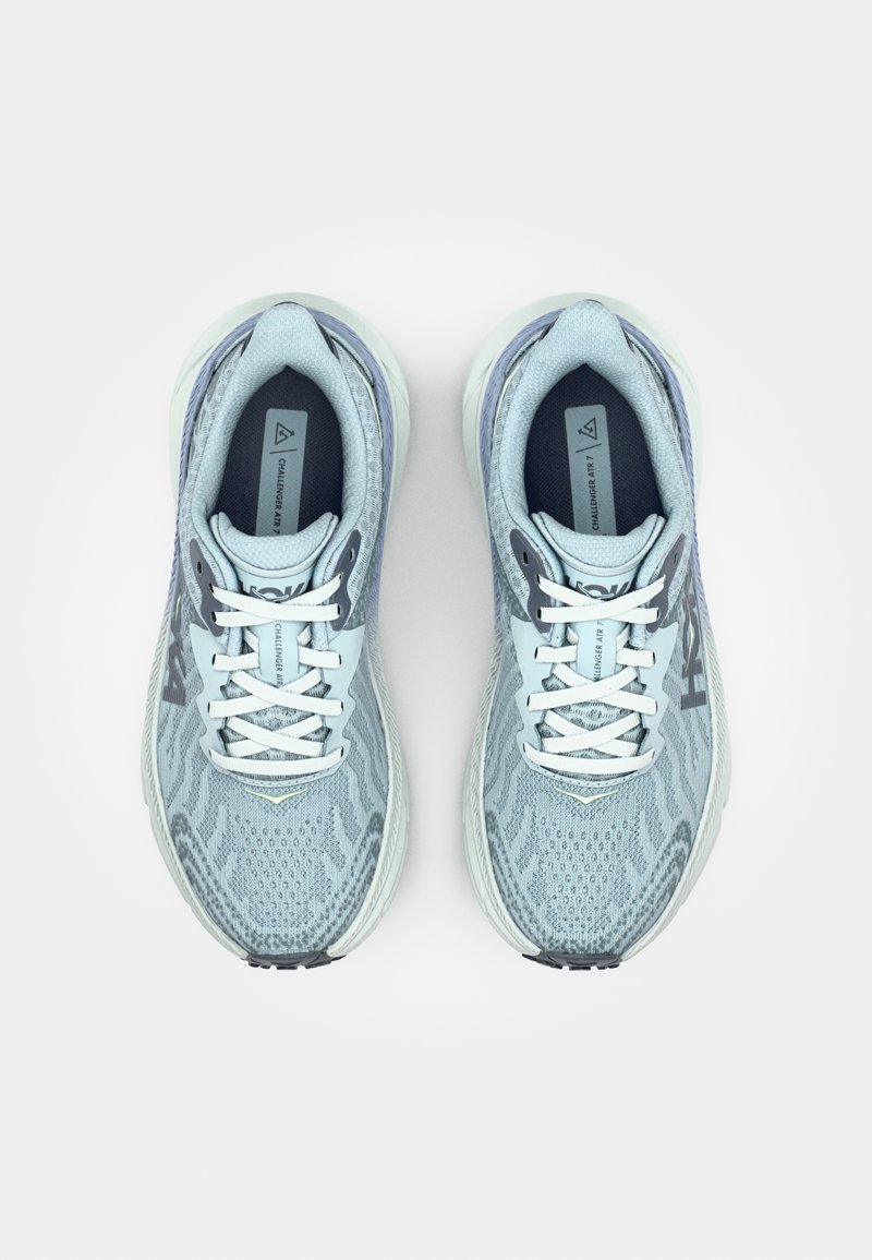 Zapatillas de running azul claro con parte superior de malla, patrón texturizado, cordones blancos y acentos grises. Presentan una suela acolchada y un detalle de logotipo.