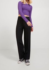 Mustat räätälöidyt housut suoralla leikkauksella, yhdistettynä violettiin pitkähihainen paitaan ja mustiin kangastennareihin. Sileä kangaspinta.