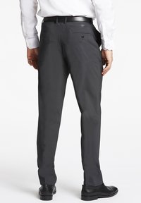 Pantaloni eleganti grigi scuri con una texture liscia, fit slim, due tasche posteriori e una cintura integrata in un design elegante. Mostrati con scarpe nere.