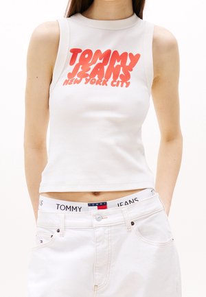 Hvid ærmeløs croptop med ribbet tekstur. Har rød grafisk tekst "TOMMY JEANS NEW YORK CITY" på fronten. Kombineret med hvide denimshorts.