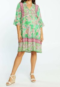Vestido floral verde con acentos rosas, que presenta un escote en V, mangas tres cuartos y un corte tipo A. Tejido ligero con un patrón texturizado.