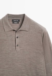 Merinowoll-Poloshirt in einem gedeckten Braunton, mit klassischem Kragen, Drei-Knopf-Leiste und einer glatten, feinen Textur.