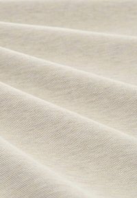 Krämfärgad tyg med en strukturerad väv, som visar försiktiga veck och en slät yta. Inga synliga mönster eller accenter.