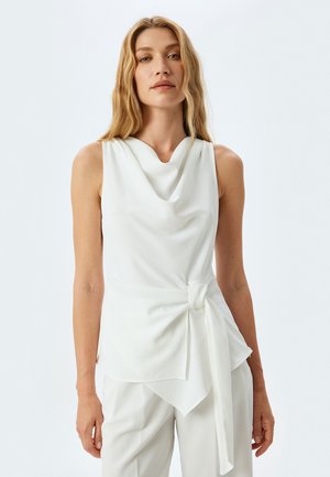 Top bianco senza maniche con scollatura drappeggiata, dettaglio a nodo in vita e tessuto morbido con silhouette fluida.