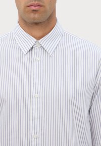 Camisa de vestir blanca con rayas verticales en azul claro, que presenta un cuello clásico y cierre frontal con botones. Tejido suave, ajuste casual.
