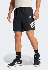 Schwarze Sportshorts mit drei weißen diagonalen Streifen und perforierten Akzenten an der Seite. Elastischer Bund und leichtes Material.