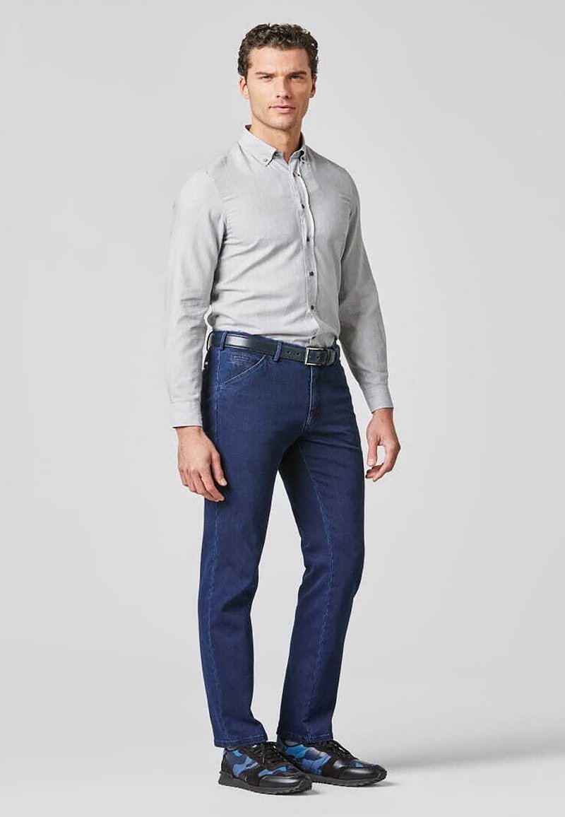 Graues Hemd mit Knopfleiste, dunkelblaue Jeans und schwarze Sneakers mit blauen Akzenten. Glattes Material mit geradem Schnitt. Keine sichtbaren Muster.