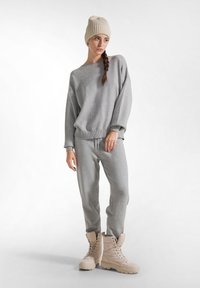 Set di felpa e pantaloni della tuta in cotone grigio, con polsini e orlo a costine. Berretto in maglia crema e stivali beige con lacci e suola spessa.