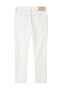 Les jeans en denim blanc présentent une coupe ajustée avec une texture lisse, des poches arrière et une étiquette beige à la taille.