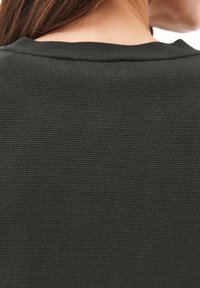 Dunkelgrüner, strukturierten Stoff mit einem gerippten Muster, der einen runden Ausschnitt aufweist. Die Ansicht zeigt die Rückseite des Kleidungsstücks.