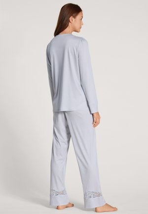 Lichtblauw pyjama set gemaakt van zachte stof; lange mouwen top en losse broek met kantaccenten aan de onderkant.