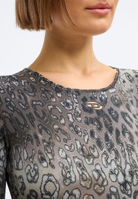 Top justo em estampa animal em tecido transparente com padrão de leopardo abstracto em tons suaves. Decote redondo com detalhe em metalizado.