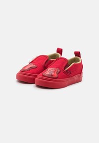 Zapatos rojos tipo slip-on hechos de lona con suela de goma, con un detalle de plástico en forma de oso en la punta y un interior acolchado.