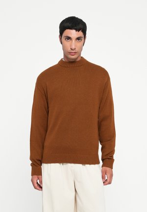 Brauner Strickpullover mit hohem Rippkragen, lockerer Passform und geripptem Saum. Das Material wirkt strukturiert und eignet sich für die Freizeit.
