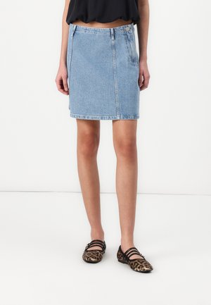 Jupe en denim bleu clair, de longueur genou, avec fermeture à boutons et zip à l'avant, de coupe droite. Assortie à des ballerines imprimées léopard.