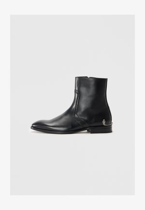 Musthave mustanahast kott, terava nina, tekstureeritud külgdetailiga, madala kandiga ja väikese dekoratiivse hõbedase maoaktsendiga kannal.