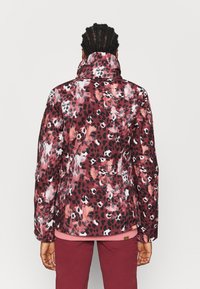 Polstret jakke i nuancer af burgundy og sort med et leopardmønster. Høj krave og lange ærmer; glat teksturfinish.