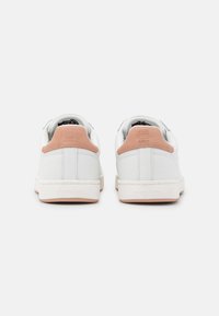 Witte sneakers met een gladde afwerking en lichtroze hielaccenten. Voorzien van een gevoerd kraagje en een gestructureerde rubberen zool.