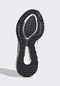 Fekete gumi outsole, textúrált talprajz- mintával, ívelt formával és középső barázdával; fehér hab középtalp a széleken látható.