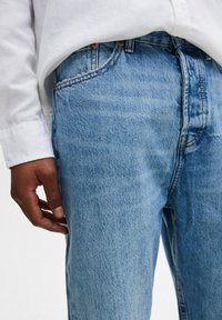 Ljusblå denimjeans med rak passform, som har kontrasterande sömmar och sidofickor. Tyget har en lätt blekt textur.