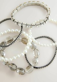 Five bracelets: silver metallic with square links and crystals, black with sequins, and pearl strands in white and gray with faceted beads.