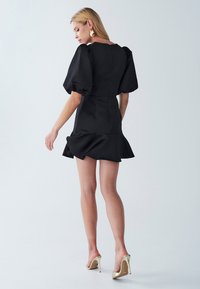 Mustat mekko, jossa on puffattuja hihoja, tiukka bodice ja levenevä helma. Valmistettu sileästä kankaasta, jossa on takavetoketju. Yhdistetty kultaisiin korkokenkiin.