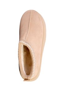 Lysebrun beige hjemmesko med blødt ruskind på ydersiden, blødt foer indvendigt og kontrasterende dekorative syninger langs topkanten.