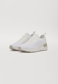 Weiße Sportschuhe aus Mesh-Gewebe mit strukturiertem Design, ausgestattet mit einem gepolsterten Kragen, Schnürverschluss und einer hellgrauen Sohle.