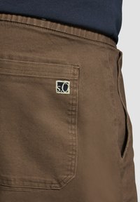 Brahno blago kratke hlače s hrbtnim žepom in oznako, ki prikazuje "s.o." logo v belem na mornarskem ozadju. Gladka tekstura, kroj za prileganje.