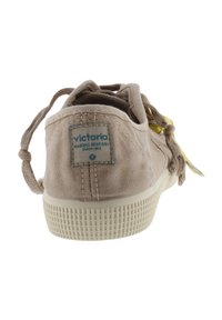 Sneaker in tela beige con suola in gomma testurizzata, linguetta posteriore e etichetta blu. Caratterizzati da lacci sottili e design minimalista.