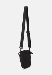 Borsa a tracolla nera realizzata in tessuto resistente. Presenta una tracolla regolabile, una forma rettangolare e un design minimalista senza loghi visibili.
