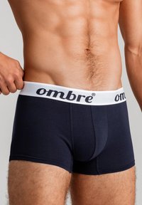 Boxerit vaaleansinisestä puuvillasta, jossa on valkoinen vyötärönauha, jossa on musta brändinimi "ombre". Tasainen pinta ja tiukka muotoilu.